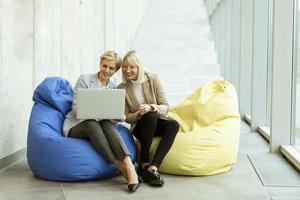 donne d'affari utilizzando il computer portatile computer su pigro borse nel il moderno ufficio foto