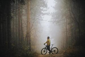 giovane uomo assunzione un' freno durante bike attraverso autunno foresta foto