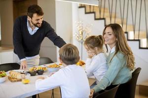 giovane contento famiglia parlando mentre avendo prima colazione a cenare tavolo foto