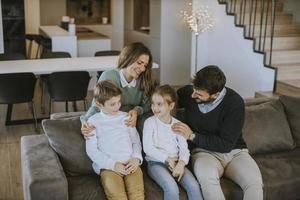 contento famiglia con Due bambini godere tempo insieme su divano nel vivente camera foto