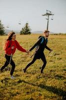 sorridente coppia a piedi con zaini al di sopra di verde colline di il seggiovia foto