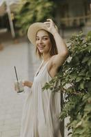 giovane donna con cappello che beve limonata fredda nel giardino del resort foto