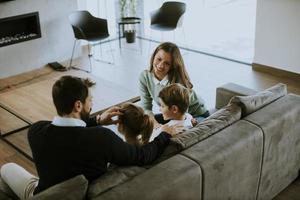 giovane famiglia Guardando tv insieme su il divano nel il vivente camera foto