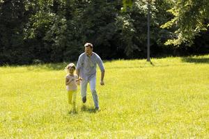 padre con figlia che si diverte sull'erba al parco foto