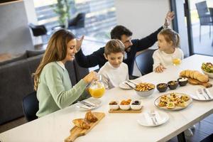 giovane contento famiglia parlando mentre avendo prima colazione a cenare tavolo foto