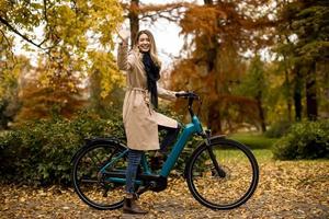 giovane donna con elettrico bicicletta nel TE autunno parco foto