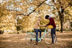 multirazziale coppia con bicicletta nel il autunno parco foto