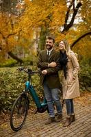 giovane coppia nel parco autunnale con bicicletta elettrica foto