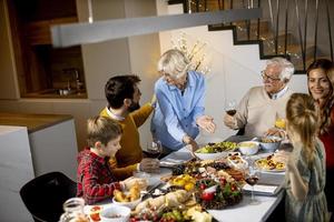 contento famiglia avendo cena con rosso vino a casa foto