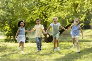 gruppo di asiatico e caucasico bambini avendo divertimento nel il parco foto