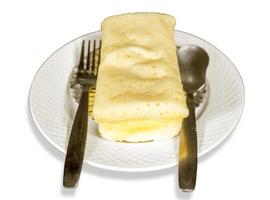 bianca cioccolato formaggio torta con cucchiaino e forchetta su cucina Foglio, bianca ceramica piatto e isolato su bianca sfondo. foto