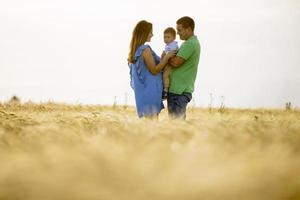 giovane famiglia con un ragazzino carino che si diverte all'aperto nel campo foto