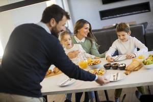 giovane contento famiglia parlando mentre avendo prima colazione a cenare tavolo foto