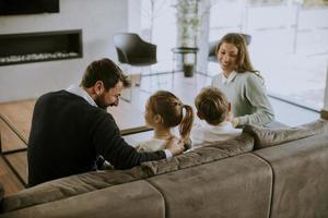 giovane famiglia Guardando tv insieme su il divano nel il vivente camera foto