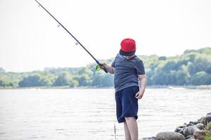 un' adolescente è pesca su il lago con un' pesca asta. ricreazione e all'aperto passeggiate nel il città parco. foto