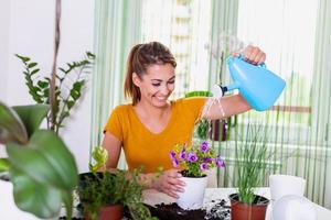 giovane donna d'affari spray impianti nel vasi di fiori. donna cura per Casa pianta. donna assunzione cura di impianti a sua casa, spruzzatura un' pianta con puro acqua a partire dal un' spray bottiglia foto