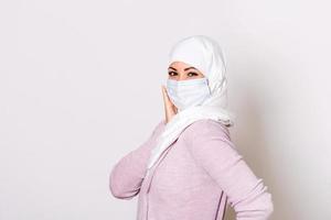 musulmano donna nel respiratorio maschera. mascherato donna con hijab mettendo su protettivo maschera. freddo, influenza, virus, tonsillite, acuto respiratorio patologia, quarantena, epidemico. covid - 19, coronavirus prevenzione foto