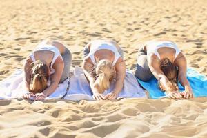 gruppo di donne praticando yoga su il spiaggia foto