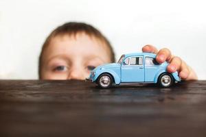 bambino giocando con il auto vicino su un' bianca sfondo foto