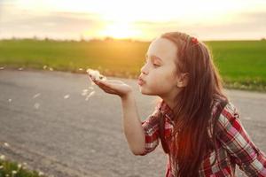 ragazza colpi su un' dente di leone foto