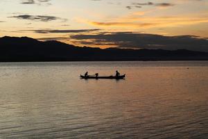 Due pescatori su il lago a partire dal un' barca a tramonto. limboto lago, gorontalo, Indonesia. bellissimo cielo nel il pomeriggio foto