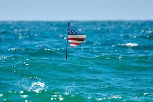 immersione Stati Uniti d'America bandiera galleggiante sopra autorespiratore diversi appena sotto il superficie. Stati Uniti d'America bandiera in piedi con pontoni nel il mare. foto