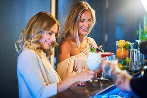 Due ragazza amici avendo bevande nel bar foto