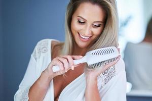 contento donna spazzolatura capelli nel bagno foto