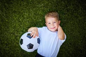 poco ragazzo praticando calcio all'aperto foto