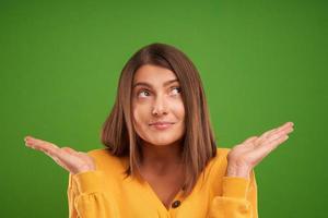 vicino su di donna nel giallo maglione pensiero e puntamento al di sopra di verde sfondo foto