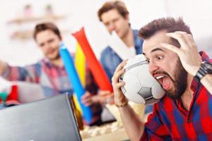 contento maschio amici applauso e Guardando gli sport su tv foto