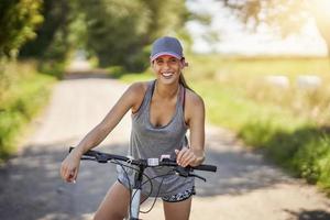 giovane contento donna su un' bicicletta nel campagna foto