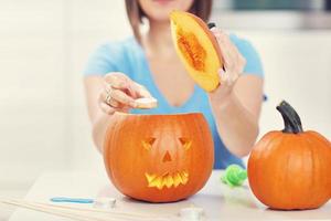 giovane donna fabbricazione jack-o-lanterna nel il cucina foto