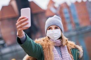 donna indossare viso maschera e assunzione autoscatto nel il città foto