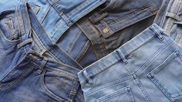 pila di coppie di denim jeans di vario blu occhiali da sole e dimensioni foto