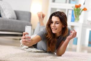 contento adulto donna utilizzando Telefono a casa nel il vivente camera foto