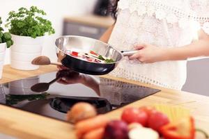 giovane donna preparazione fritte verdure nel cucina foto