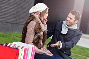 giovane uomo mostrando disapprovazione per donna con molti shopping borse foto