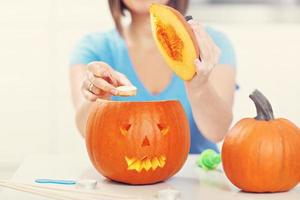 giovane donna fabbricazione jack-o-lanterna nel il cucina foto