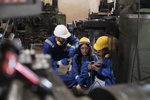 doloroso incidente nel industriale produzione lavorazione dei metalli, africano americano femmina lavoratore ferito sua gamba, maschio ingegnere e collega squadra aiutato primo aiuto con cura a produzione macchinari fabbrica. foto