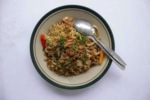 mie goreng jawa o bakmi jawa o Giava spaghetto con cucchiaio e forchetta. indonesiano tradizionale strada cibo tagliatelle a partire dal centrale Giava o Yogyakarta, Indonesia su bianca sfondo foto