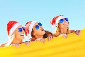 gruppo di ragazze nel Babbo Natale cappelli avendo divertimento su il spiaggia foto