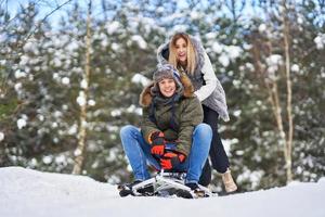 coppia avendo divertimento con slitta su neve nel inverno foto