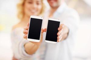 coppia mostrando loro smartphone foto