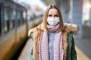 adulto donna a treno stazione indossare maschere dovuto per covid-19 restrizioni foto