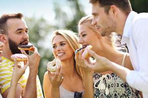 gruppo di amici mangiare ciambelle all'aperto foto