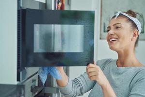 giovane donna pulizia forno nel il cucina foto