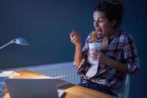 Affamato alunno mangiare spaghetto mentre apprendimento a casa foto