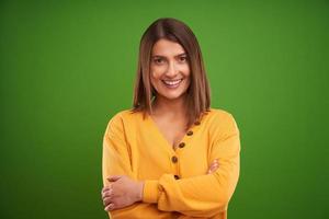 vicino su di donna nel giallo maglione guardare a telecamera al di sopra di verde sfondo foto