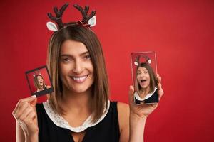 donna nel Natale umore confrontando immediato immagini per smartphone telecamera al di sopra di rosso foto